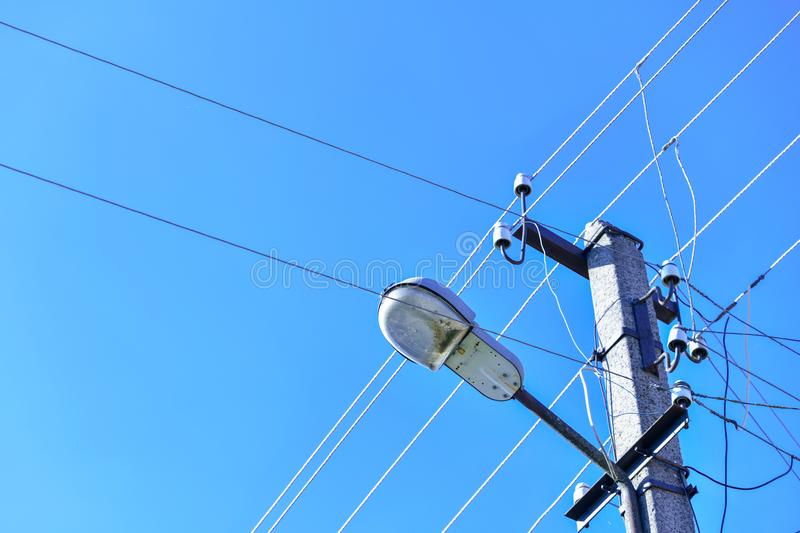 antiguo poste eléctrico de hormigón para la transmisión electricidad por cable con luz sobre un fondo cielo azul turbio 168670770